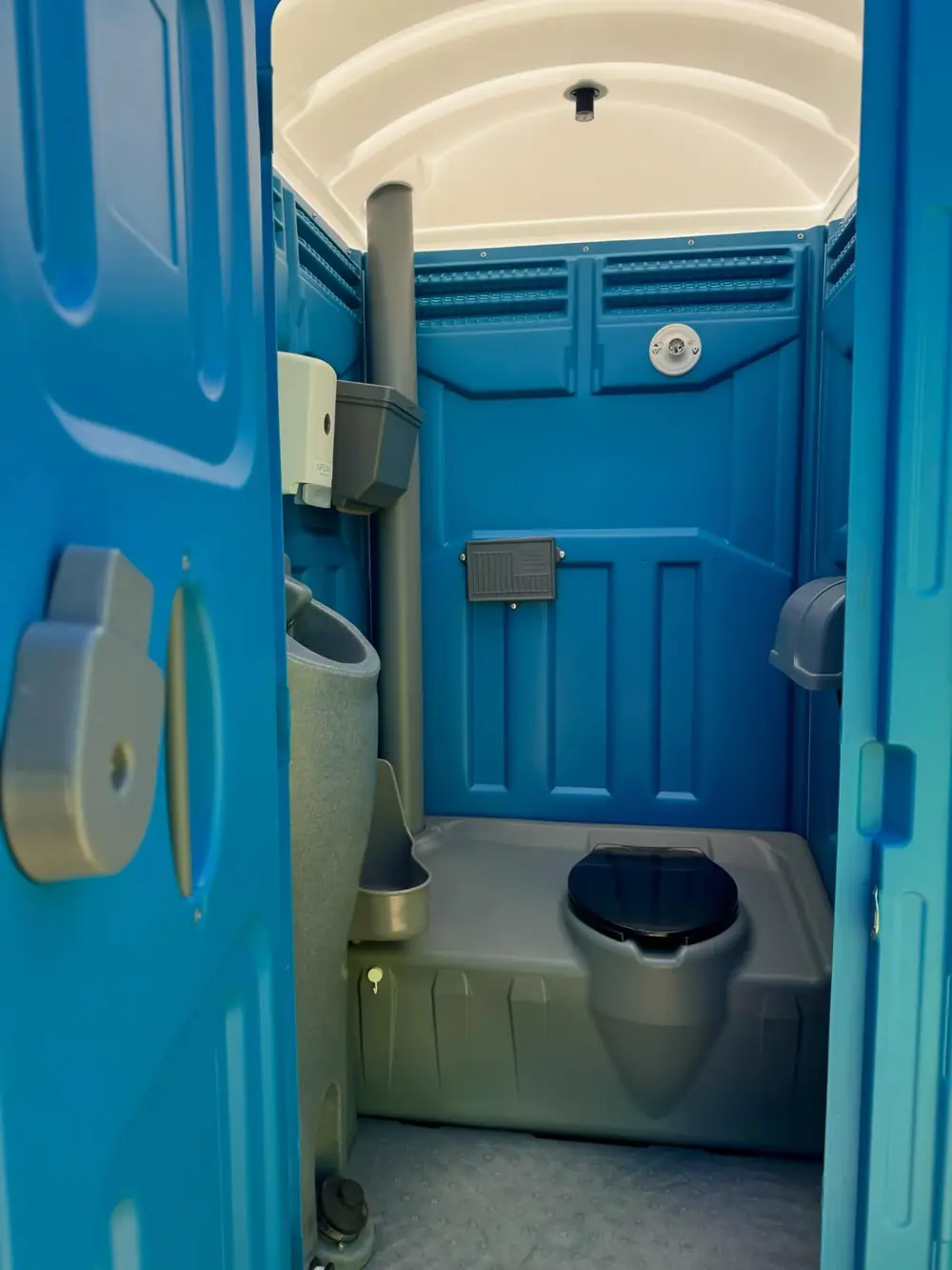 Clean interior of a standard portable toilet with urinal and vents